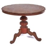 A Continental walnut tripod table, 19th c, the round top with wavy edge on red stained pillar and