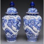 A pair of Japanese blue and white Imari jars and covers, early 20th c, moulded with dragons, 42cm