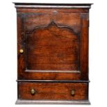 An oak mural spice cupboard,  enclosed by an ogee arch panelled door, a drawer below, 61.5cm; 21.5 x