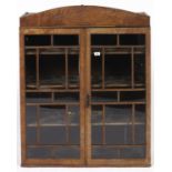 A Regency mahogany bookcase, c1820, with arched figured cornice applied lozenge shaped reeded panel,