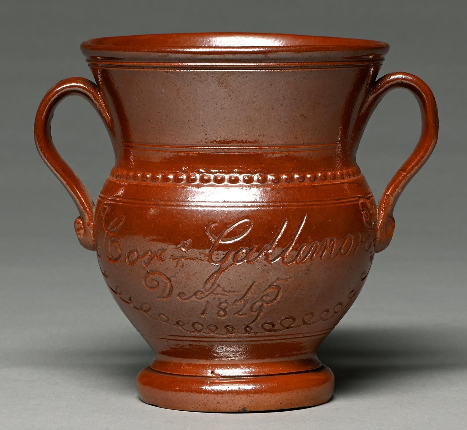 A Derbyshire saltglazed brown stoneware loving cup, Chesterfield or Brampton, dated 1829, of typical