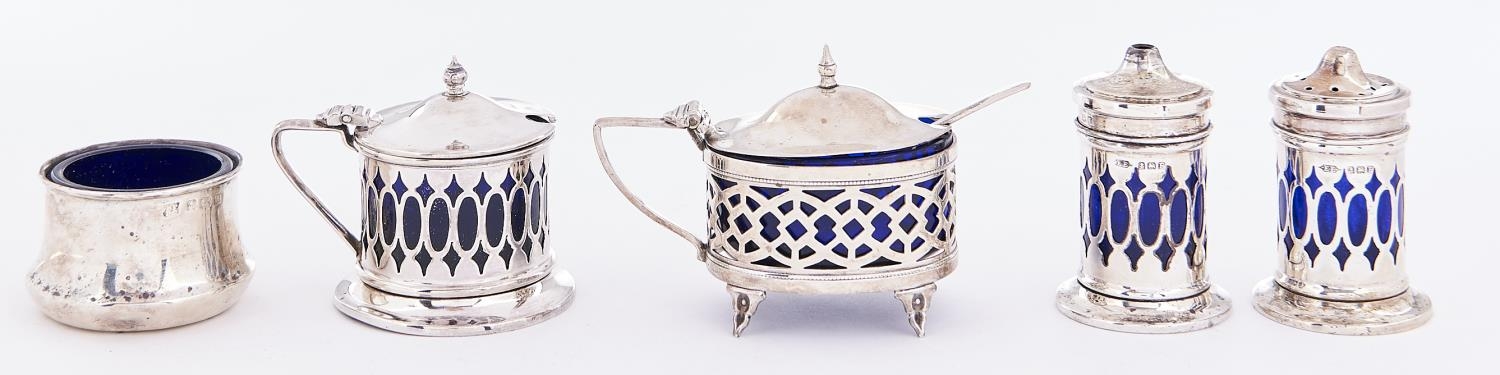 A George V three piece pierced silver condiment set, blue glass liner, pepperette 50mm h, by E