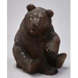 A Swiss carved and stained limewood sculpture of a bear, c1900, seated on his haunches with alert
