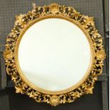 A circular Florentine  giltwood mirror, early 20th c, the frame of scrolling foliage with double