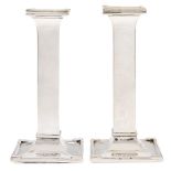 A pair of George V silver candlesticks, of plain square design on dished foot, nozzles, 15cm h,