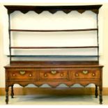 A George III oak dresser,  early 19th c, flared cornice and arched frieze with shelved back, the