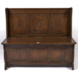 n  oak settle,    carved with portcullis, hinged boarded seat,  three panel front, on shaped,