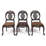A set of three Indian carved blackwood side chairs, late 19th c, the back formed of two c-scrolls