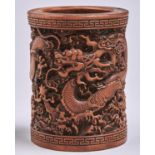 A Chinese bamboo brush pot, carved with dragons beneath key fret borders, 12cm h Ascending shrinkage