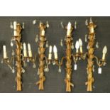 A set of four giltwood, plaster and gold painted metal foliate three branch wall lights, early
