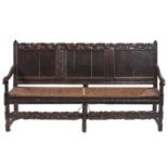 A Charles II panelled oak settle, late 17th c, with boldly carved leafy scrolling crest rail and