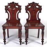 A pair of Victorian carved mahogany shield back hall chairs, on tapering turned forelegs, seat