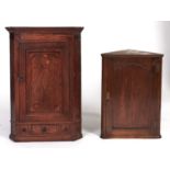 A George III oak hanging corner cupboard, c1780, flared cornice, mahogany veneered frieze, the