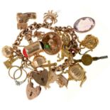 A gold charm bracelet, with a varied collection of gold charms, two padlocks and a base metal
