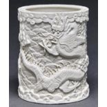 A Chinese blanc de chine brush pot, carved with dragons and fish between wave borders, 12cm h,