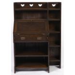 A Liberty & Co oak bureau, with shaped wings, shelved upstand pierced with three hearts, panelled
