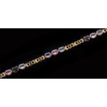 A gold bracelet, with groups of three vary coloured sapphires at intervals and heart shaped links,