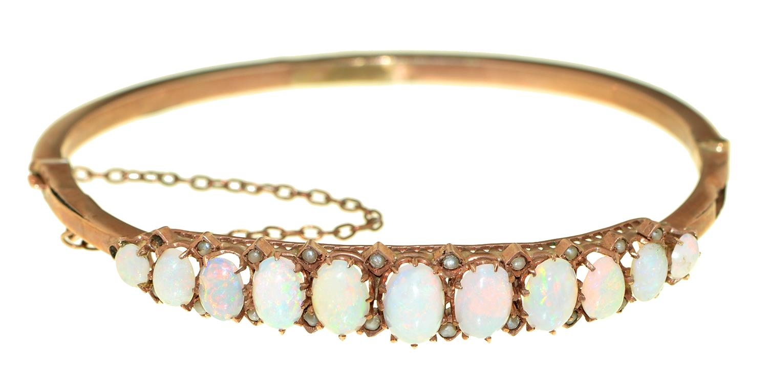 An opal and split pearl bangle, early 20th c, in gold, 81mm, marked 9ct, 6g Dented and worn, opals