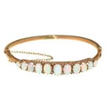 An opal and split pearl bangle, early 20th c, in gold, 81mm, marked 9ct, 6g Dented and worn, opals