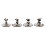 A set of four silver place or menu stands in the form of seated cherub musician, on flared octagonal