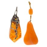 Two amber pendants, one silver mounted, the second 82mm, 65.8g Good condition