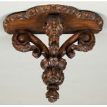 A carved walnut wall bracket, 19th/early 20th c,  with oak shelf, of three recurved and beaded