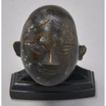 An Indian miniature patinated brass stylised model of a human head, with benign expression, 85mm h