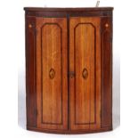 A George III oak hanging corner cupboard, c1800, enclosed by a pair of doors  flanked by mahogany