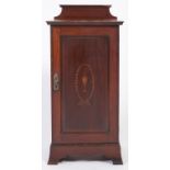 An Edwardian mahogany pot cupboard, with barber pole stringing, the panelled door inlaid with urn