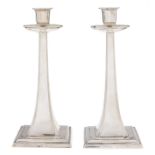 A pair of George V silver candlesticks, in art and crafts style, with drip pan, on square foot, 24cm