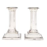 A pair of George V silver dwarf columnar candlesticks, on beaded square foot, nozzles, 13cm h, by