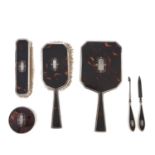 A George V nine piece silver and tortoiseshell inset brush and manicure set,  hand mirror 22.5cm