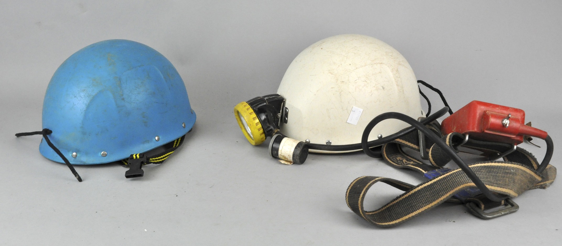 Two caving helmets with a battery pack