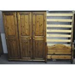 A Ducal three door pine wardrobe, 140cm wide and a pine bed frame,