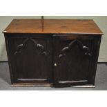 A pitch pine cupboard with Gothic ecclesiastical doors enclosing a wine rack fitted interior.