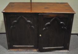 A pitch pine cupboard with Gothic ecclesiastical doors enclosing a wine rack fitted interior.