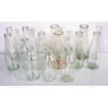 A collection of sixteen glass milk bottles. Tallest measures; 23cm.