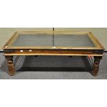 An Indian hard wood glass topped coffee table with iron decoration,