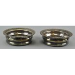 A pair of silver plated wine coasters retailed by Harrod's, mahogany base,