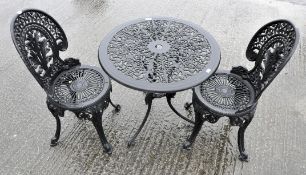 A cast aluminium painted black garden table and chairs,