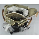 A plastic lined canvas fishing bag with two Mitchell fly reels, spare spools,