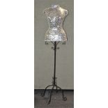 A mirror inlaid decorative mannequin on a wrought iron stand,