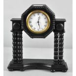 An ebonized mantle clock, with bobbin turned columns and Roman numerals denoting hours,