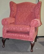 A large 18th century style wing armchair with scroll arms raised on mahogany cabriole legs,