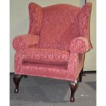 A large 18th century style wing armchair with scroll arms raised on mahogany cabriole legs,