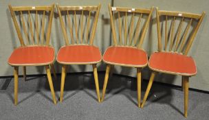 A set of four mid 20th Century retro vintage beech wood rail back dining chairs having red vinyl