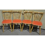 A set of four mid 20th Century retro vintage beech wood rail back dining chairs having red vinyl