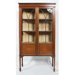 An Edwardian mahogany display cabinet inlaid with ribbon detailing, raised on four feet,