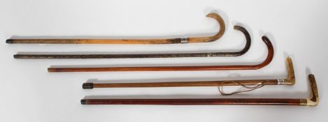 A collection of wooden walking sticks, two with silver collars, one with a bone handle,