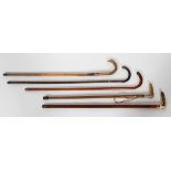 A collection of wooden walking sticks, two with silver collars, one with a bone handle,